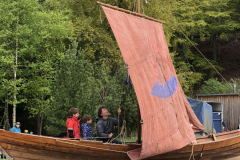 Henry Fosbrooke giving the kids a go at hoisting the sail in his wooden boat